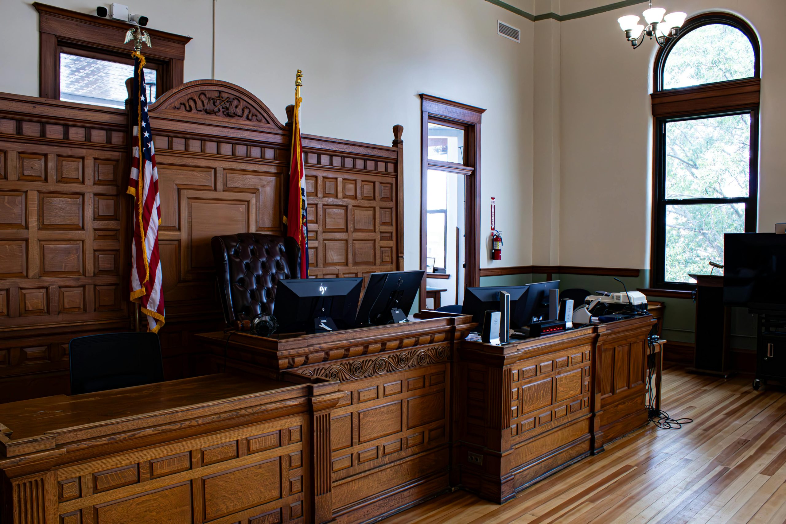 Empty courtroom in Wichita, KS with judge’s bench and American flag – representing the legal process supported by Case Bail Bonds.